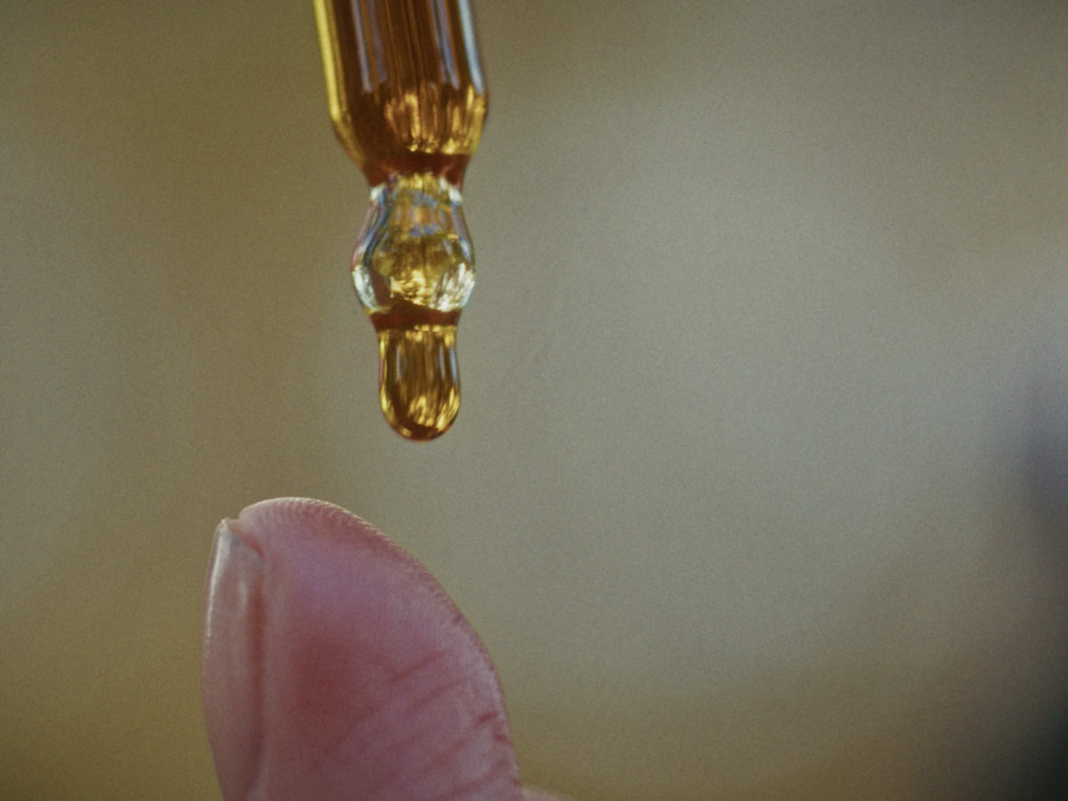 Une goutte d'huile qui coule sur un doigt